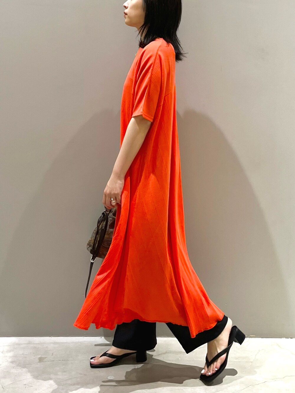 レッド系のワンピース、ブルー系のショルダーバッグ、ブラック系のサンダルを着用したレディースの夏コーディネートの3枚目の写真