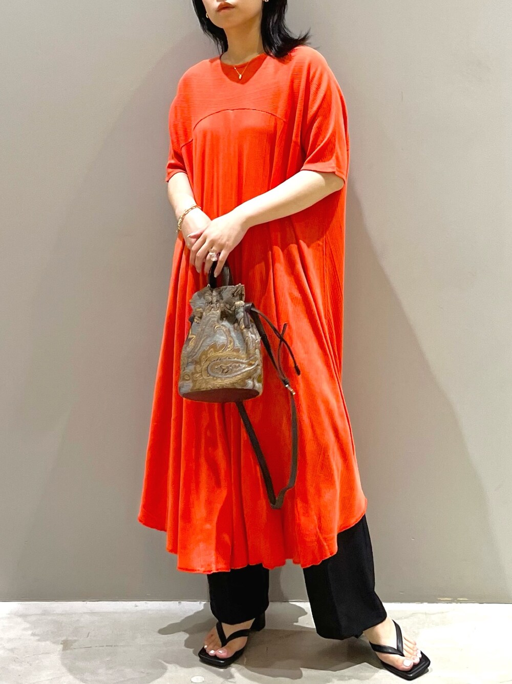 レッド系のワンピース、ブルー系のショルダーバッグ、ブラック系のサンダルを着用したレディースの夏コーディネートの2枚目の写真