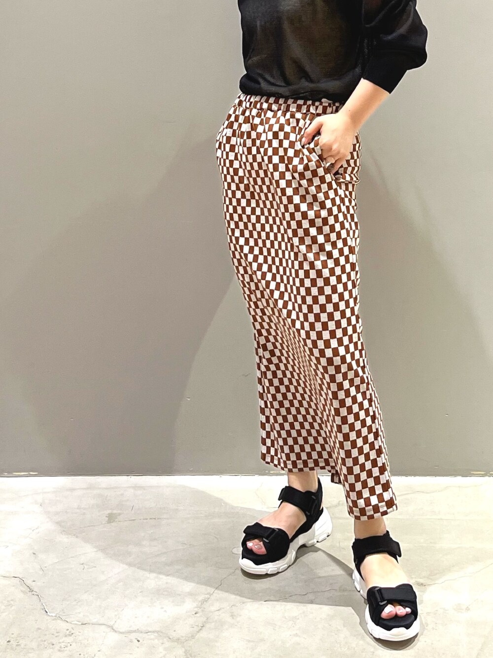 ブラック系のサンダル、ブラック系のニット/セーター、ゴールド系のイヤリングを着用したレディースの夏コーディネートの5枚目の写真