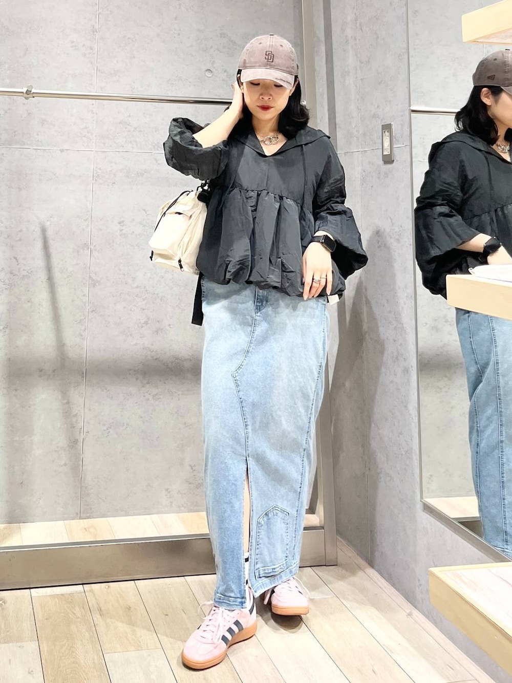 ホワイト系のショルダーバッグ、ブルー系のデニムスカート、ブラウン系のキャップを着用したレディースの冬コーディネートの1枚目の写真