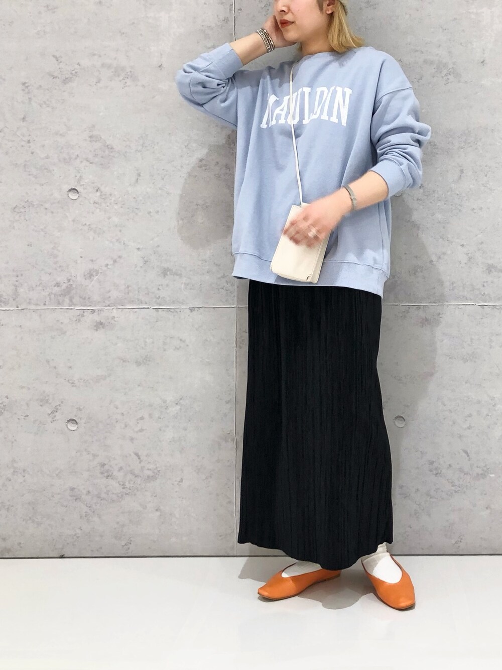 ホワイト系のショルダーバッグ、オレンジ系のパンプス、ブルー系のスウェットを着用したレディースの冬コーディネートの2枚目の写真