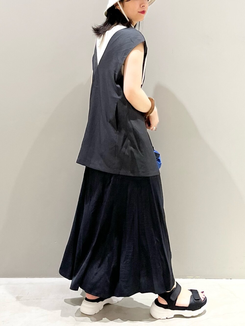 ブルー系のショルダーバッグ、ブラック系のサンダル、ブラック系のスカートを着用したレディースの夏コーディネートの2枚目の写真