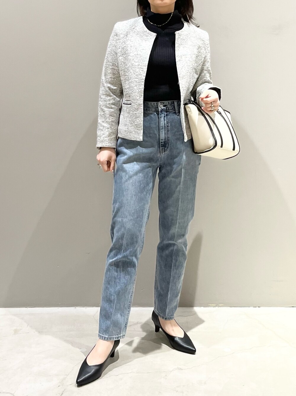 ブルー系のデニムパンツ、ブラック系のパンプス、ホワイト系のショルダーバッグを着用したレディースの冬コーディネートの1枚目の写真