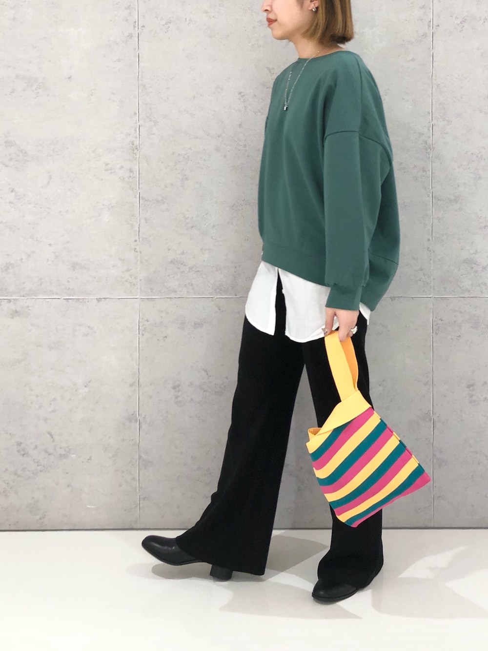 イエロー系のハンドバッグ、ブラック系のパンツ、グリーン系のスウェットを着用したレディースの冬コーディネートの3枚目の写真
