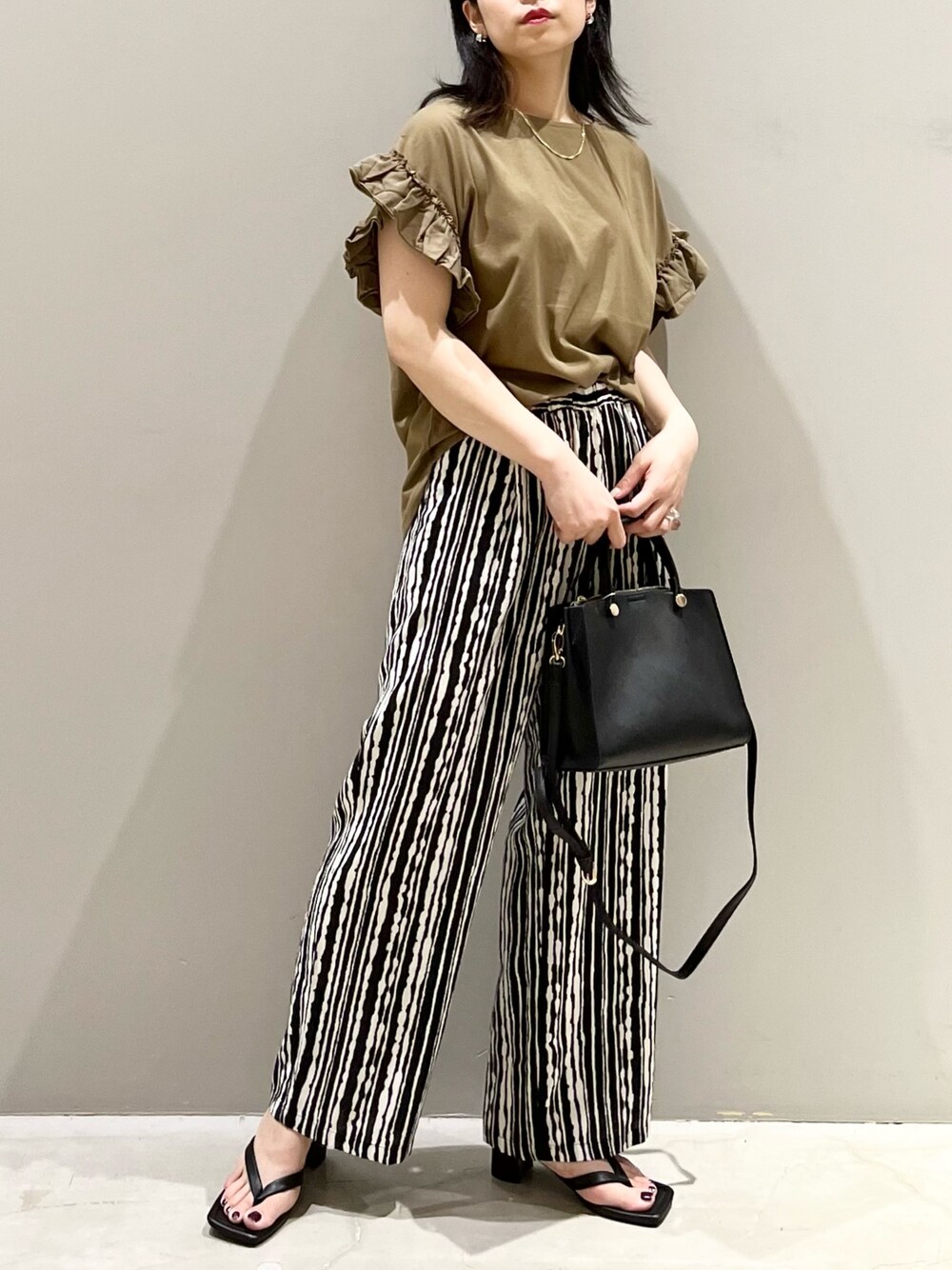 グリーン系のTシャツ/カットソー、ブラック系のサンダル、ブラック系のショルダーバッグを着用したレディースの夏コーディネートの5枚目の写真