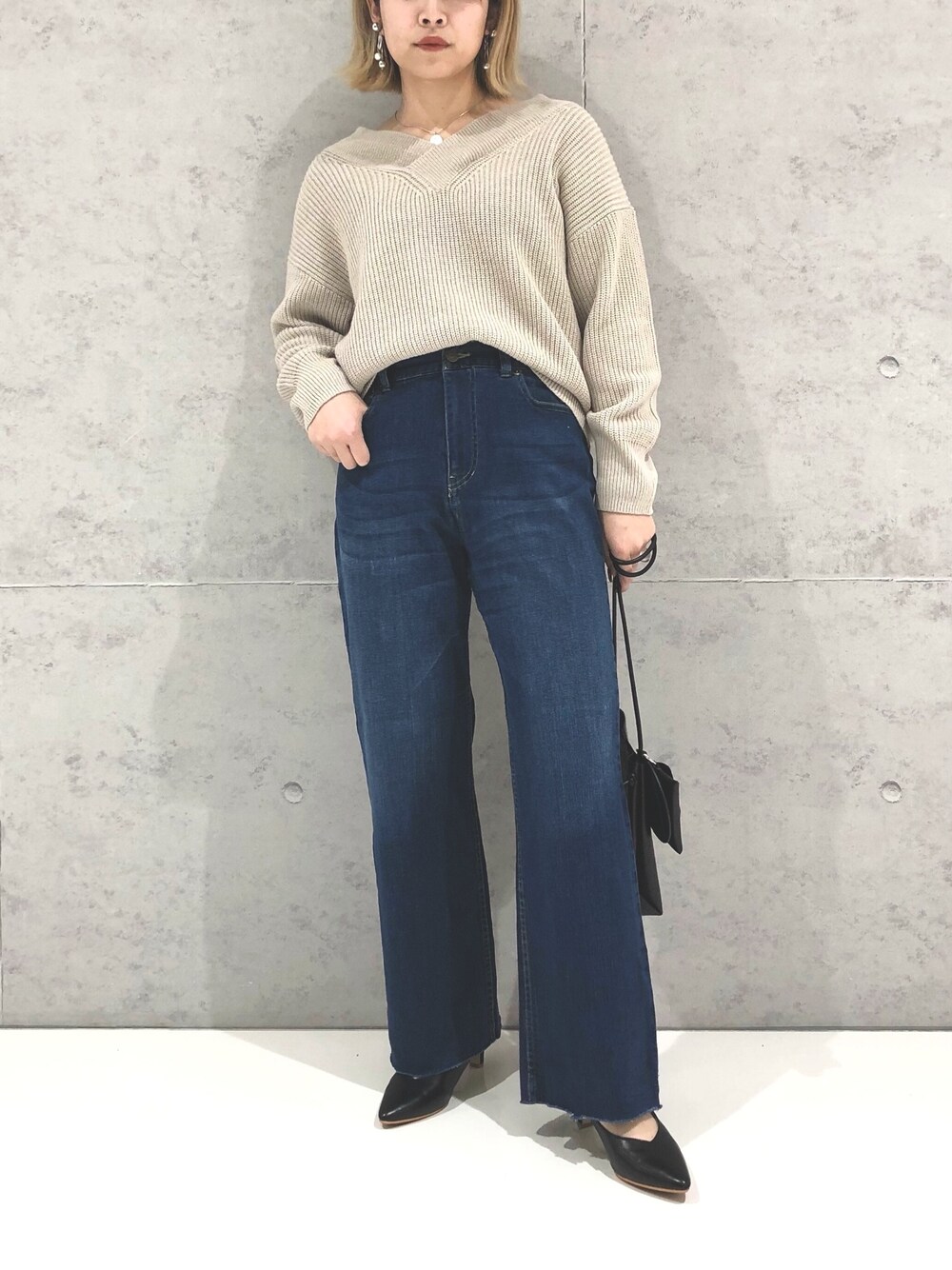 ブルー系のデニムパンツ、ブラック系のパンプス、ブラック系のショルダーバッグを着用したレディースの冬コーディネートの3枚目の写真