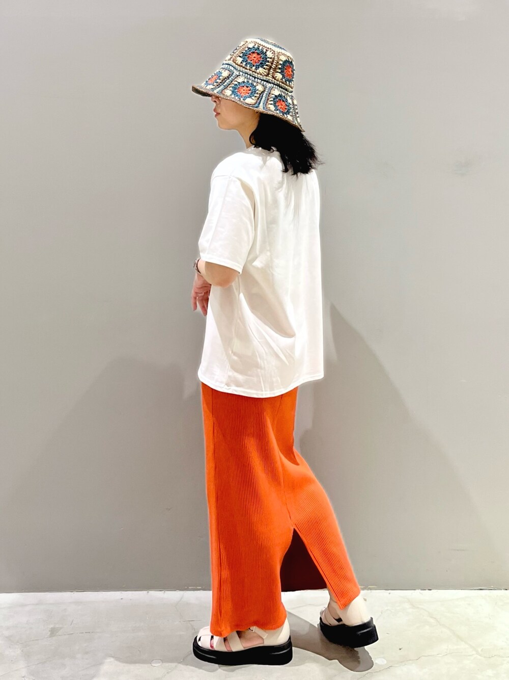 オレンジ系のスカート、ホワイト系のサンダル、グリーン系のTシャツ/カットソーを着用したレディースの夏コーディネートの4枚目の写真