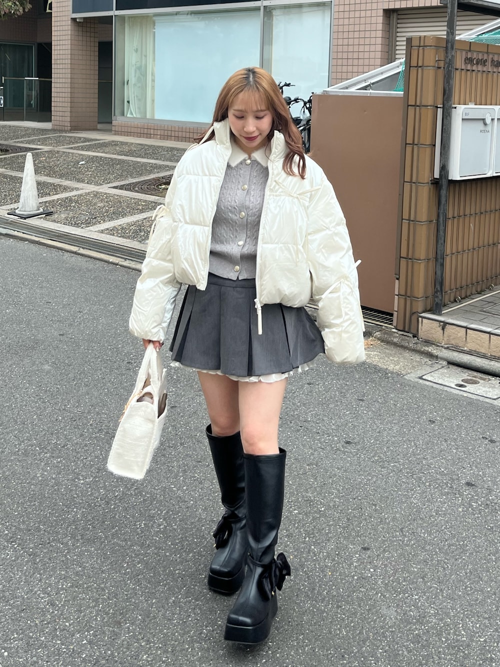 ホワイト系のダウンジャケット/コート、グレー系のカーディガン/ボレロ、グレー系のスカートを着用したレディースの秋コーディネートの1枚目の写真
