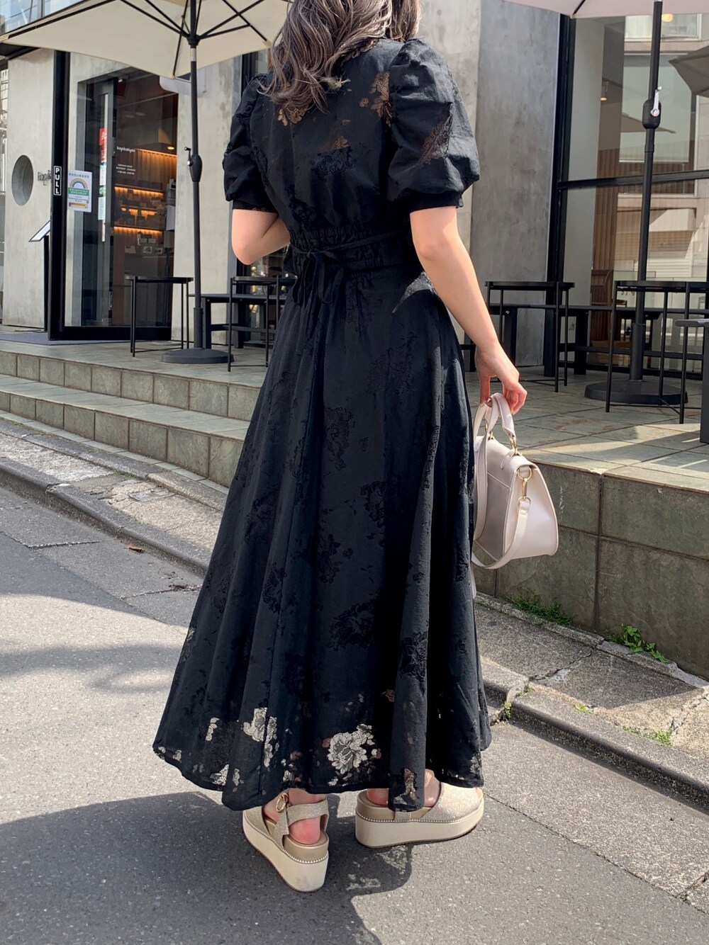 ブラック系のシャツ/ブラウス、ブラック系のスカート、ゴールド系のサンダルを着用したレディースの春コーディネートの2枚目の写真