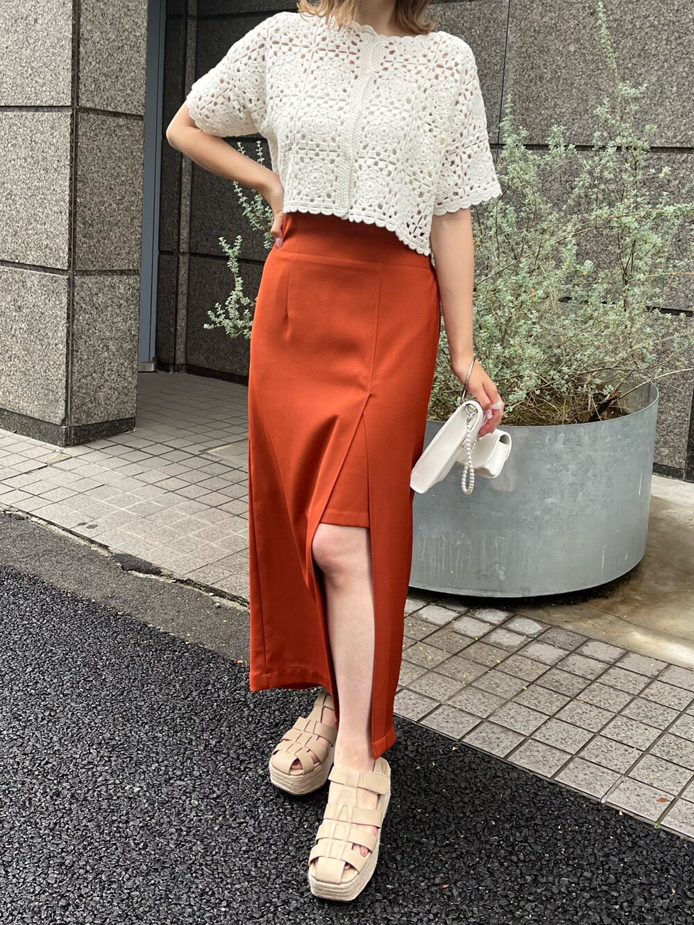 ホワイト系のカーディガン/ボレロ、オレンジ系のスカート、ベージュ系のサンダルを着用したレディースの夏コーディネートの1枚目の写真