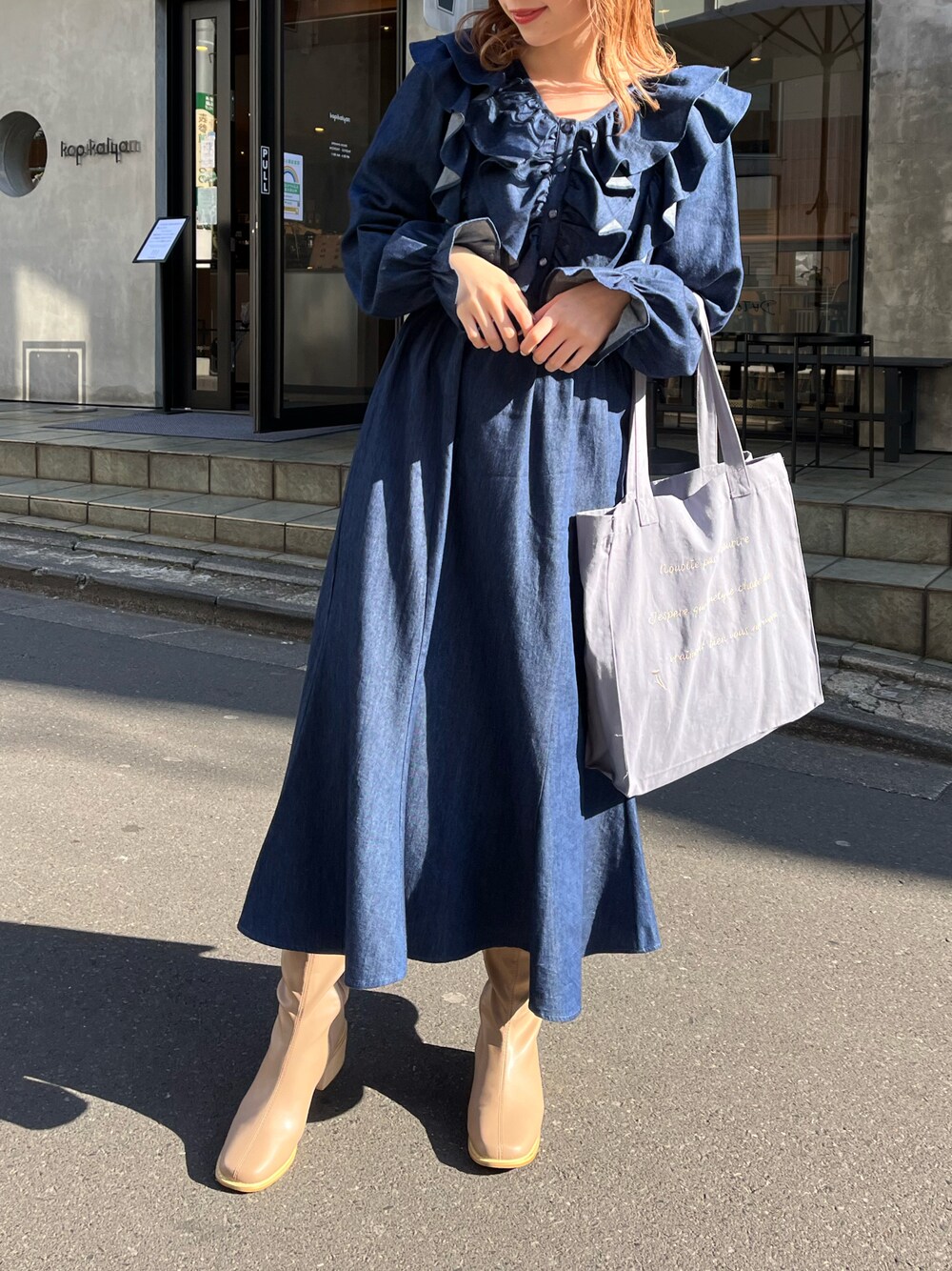 ブルー系のワンピース、ブルー系のトートバッグ、ベージュ系のブーツを着用したレディースの冬コーディネートの1枚目の写真