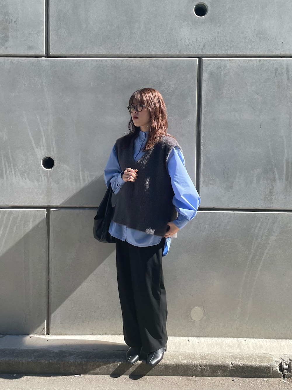 グレー系のベスト、ブルー系のシャツ/ブラウス、ブラック系のハンドバッグを着用したレディースの冬コーディネートの1枚目の写真