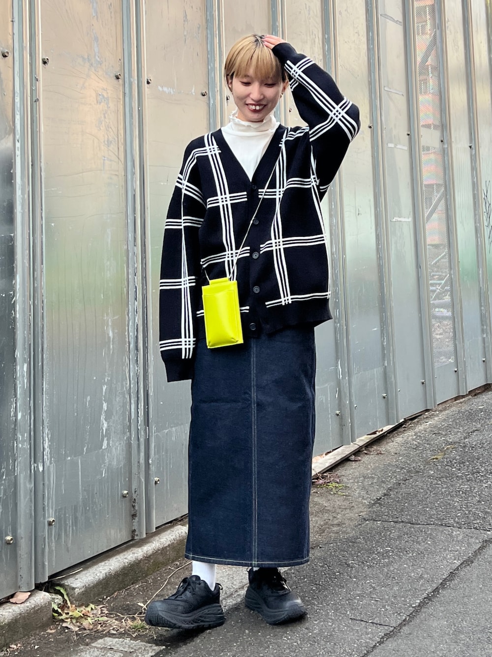 ブラック系のカーディガン/ボレロ、ブルー系のデニムスカート、グリーン系のショルダーバッグを着用したレディースの冬コーディネートの1枚目の写真