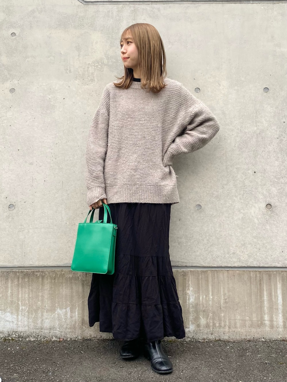 ブラック系のスカート、ホワイト系のTシャツ/カットソー、グレー系のニット/セーターを着用したレディースの冬コーディネートの1枚目の写真