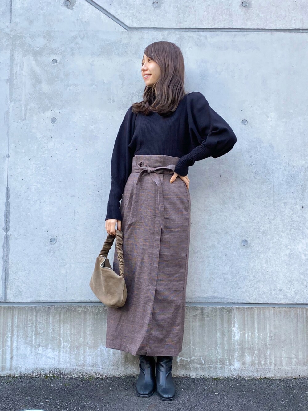 ブラック系のニット/セーター、ブラック系のスカート、ブラック系のブーツを着用したレディースの秋コーディネートの1枚目の写真