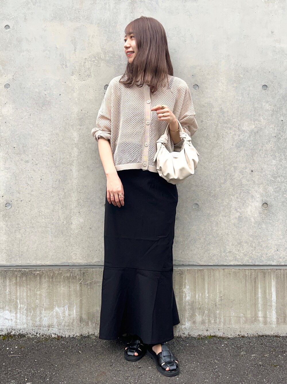 ベージュ系のカーディガン/ボレロ、ブラック系のスカート、ブラック系のサンダルを着用したレディースの春コーディネートの1枚目の写真
