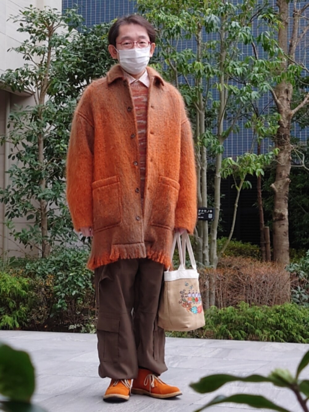 オレンジ系のその他アウター、ベージュ系のトートバッグ、ブラウン系のカーゴパンツを着用したメンズの冬コーディネートの1枚目の写真