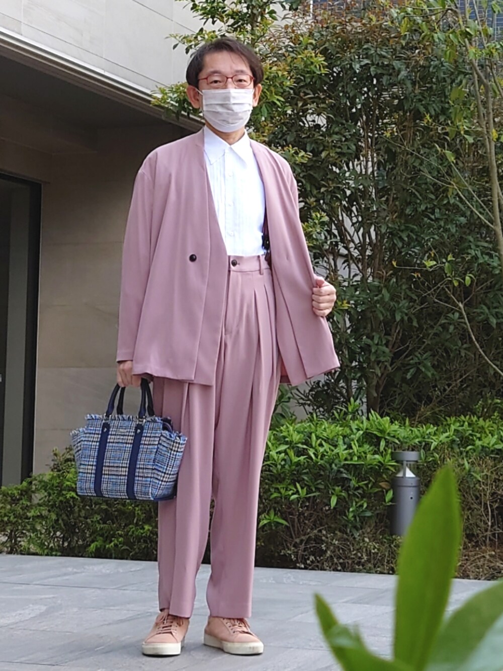 ブルー系のハンドバッグ、ピンク系のパンツ、ピンク系のノーカラージャケットを着用したメンズの春コーディネートの1枚目の写真