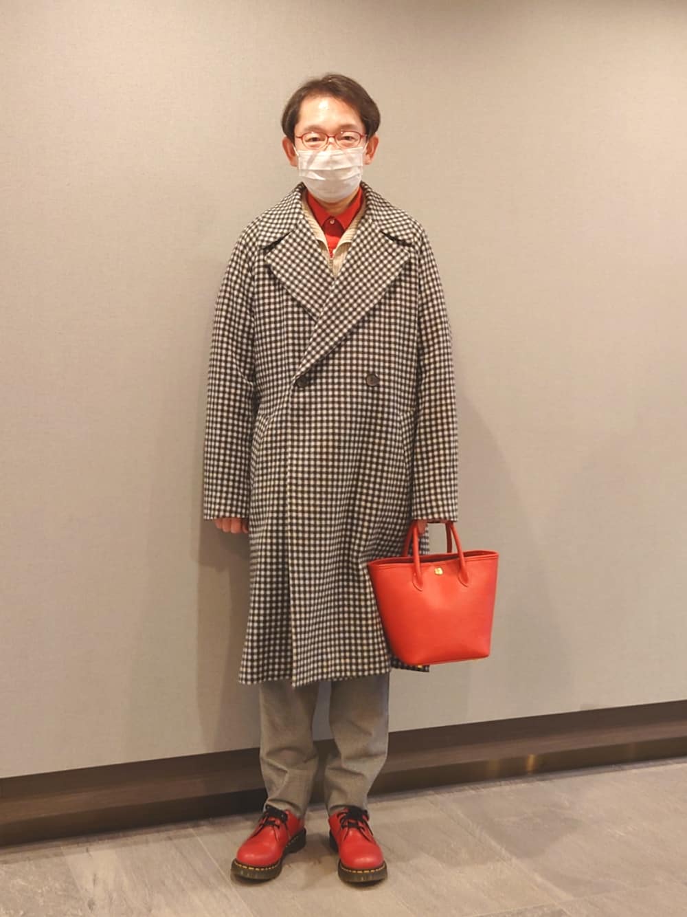 レッド系のハンドバッグ、レッド系のドレスシューズ、グレー系のパンツを着用したメンズの春コーディネートの1枚目の写真