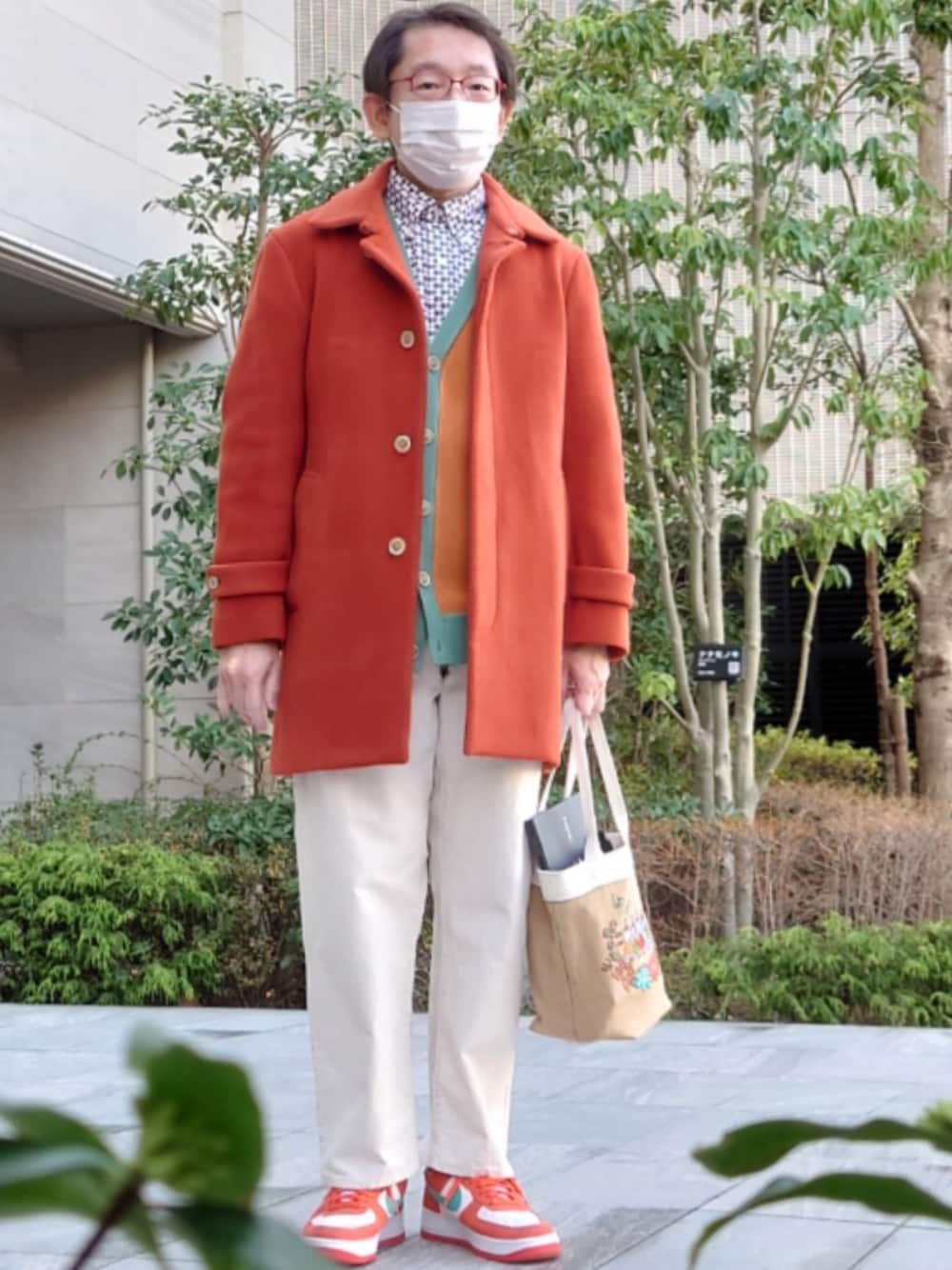 ホワイト系のパンツ、ベージュ系のトートバッグ、オレンジ系のスニーカーを着用したメンズの冬コーディネートの1枚目の写真