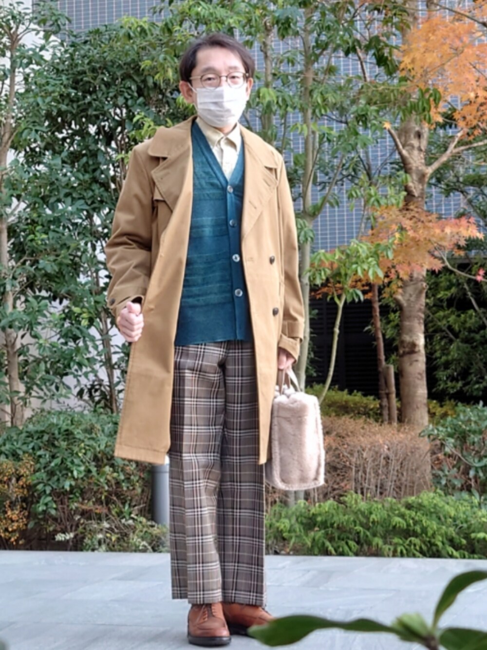 イエロー系のトレンチコート、ベージュ系のハンドバッグ、ブラウン系のその他パンツを着用したメンズの冬コーディネートの1枚目の写真