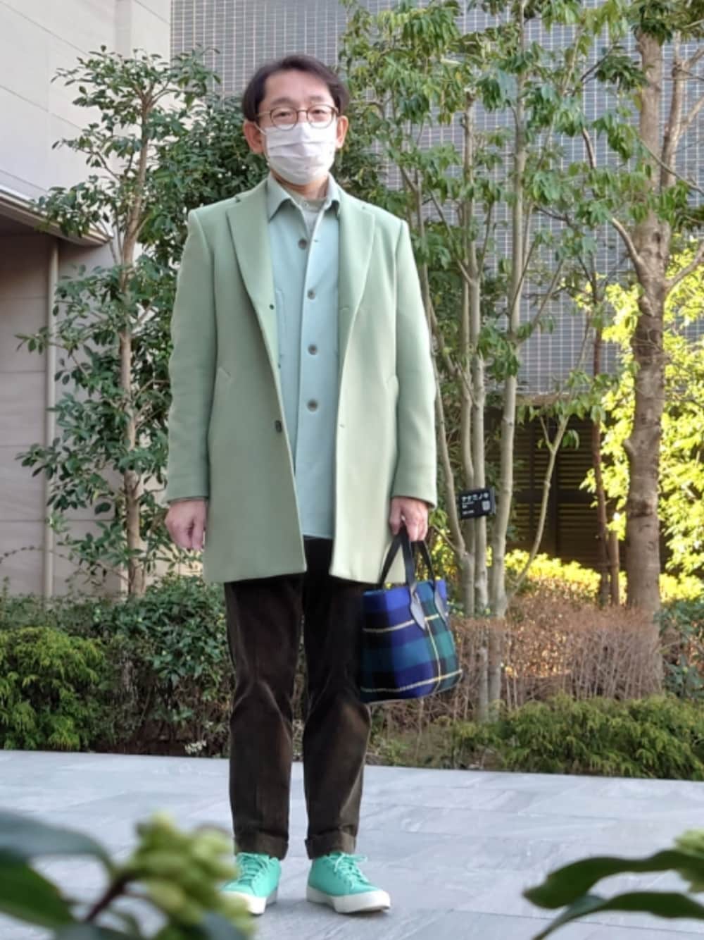 ブルー系のショルダーバッグ、グリーン系のパンツ、グリーン系のスニーカーを着用したメンズの冬コーディネートの1枚目の写真