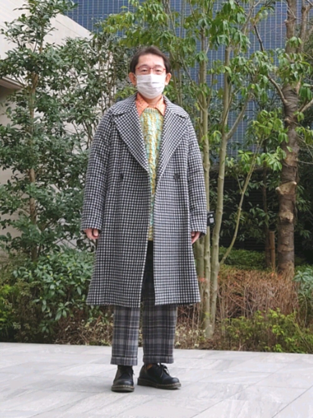 ブラック系のステンカラーコート、グリーン系のニット/セーター、グレー系のその他パンツを着用したメンズの冬コーディネートの1枚目の写真