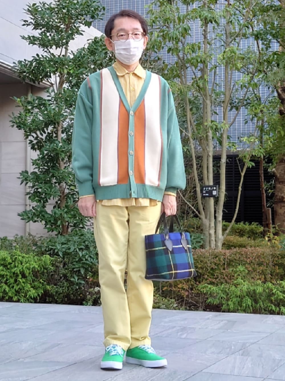 イエロー系のパンツ、ブルー系のショルダーバッグ、グリーン系のシューズを着用したメンズの秋コーディネートの1枚目の写真