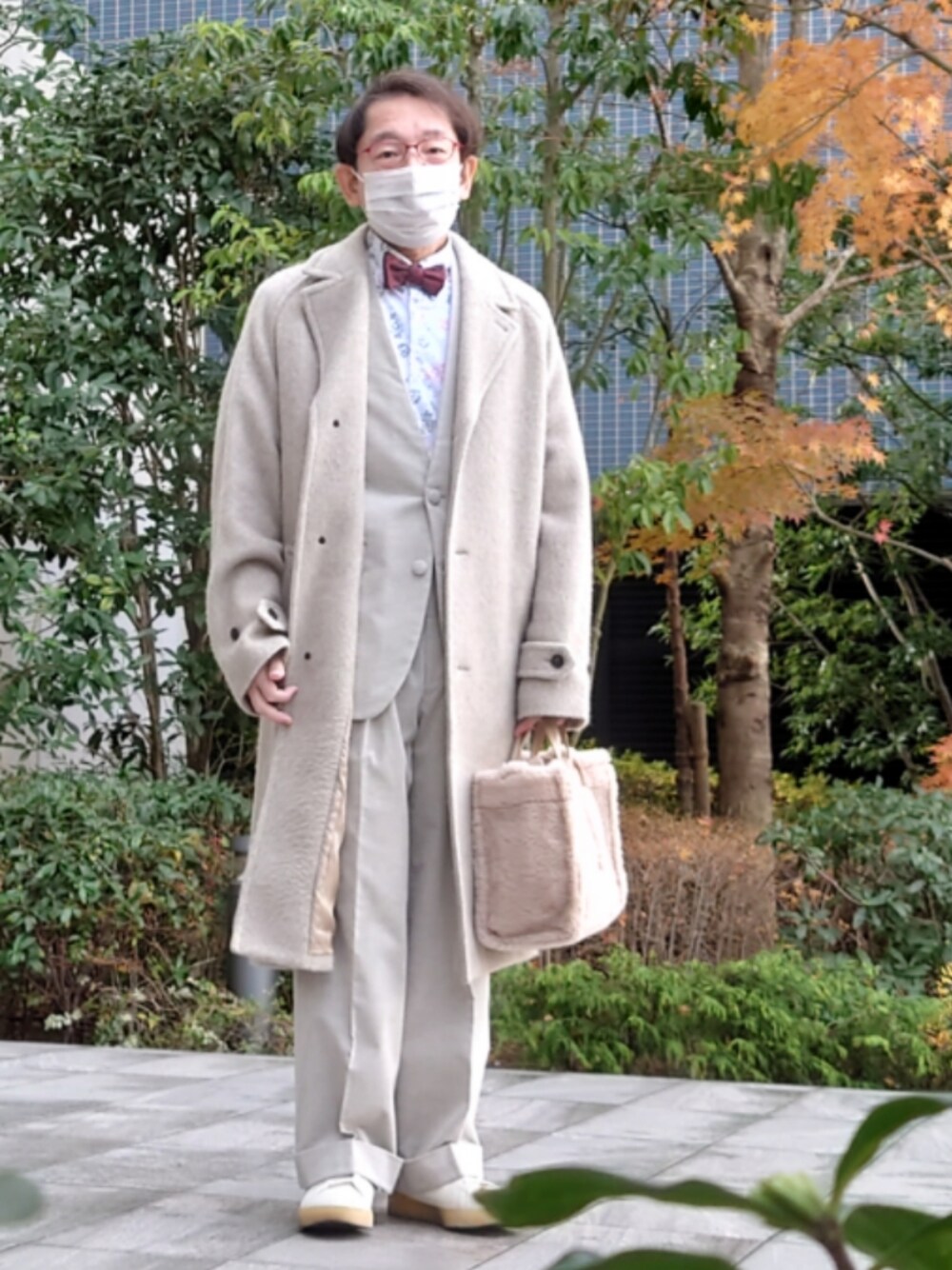 ベージュ系のノーカラージャケット、ベージュ系のハンドバッグ、ベージュ系のパンツを着用したメンズの冬コーディネートの1枚目の写真