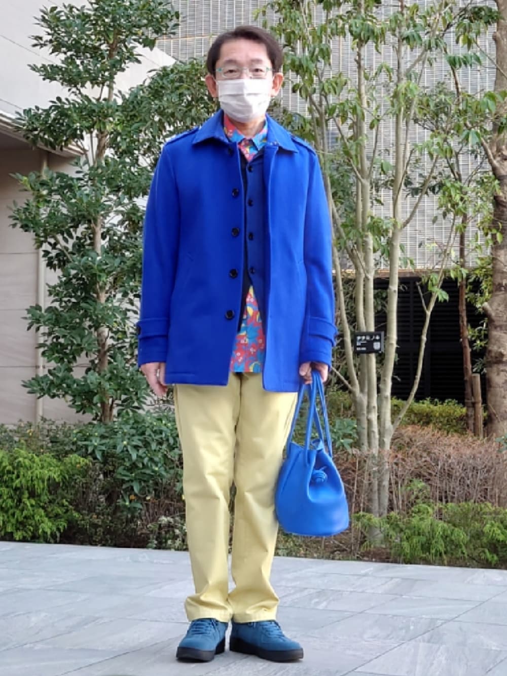 イエロー系のパンツ、ブルー系のハンドバッグ、ブルー系のシューズを着用したメンズの冬コーディネートの1枚目の写真