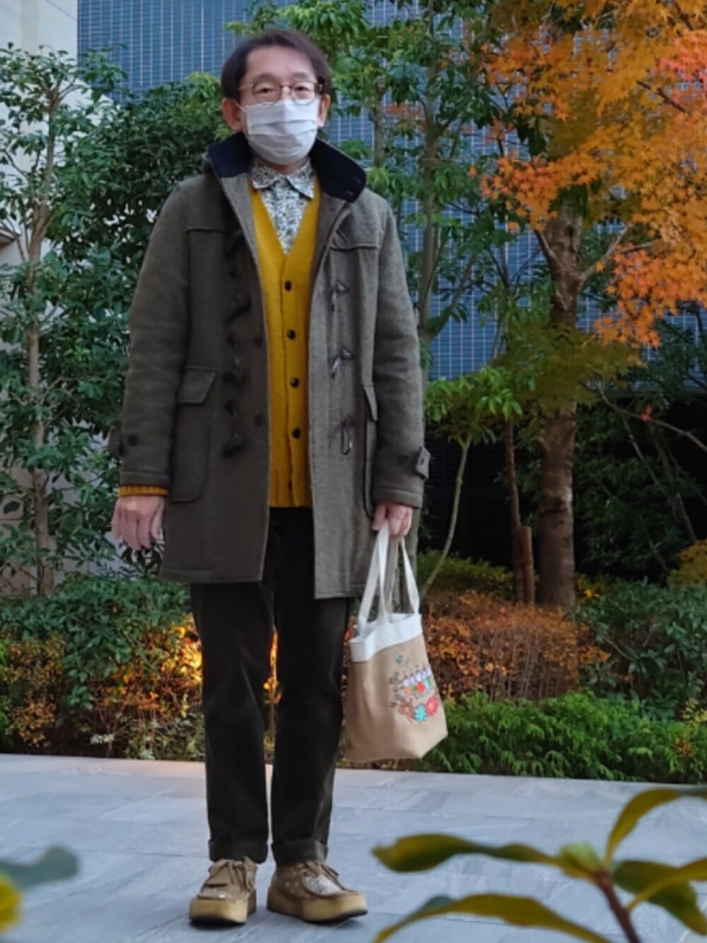 グリーン系のパンツ、ベージュ系のモカシン/デッキシューズ、ベージュ系のトートバッグを着用したメンズの冬コーディネートの1枚目の写真