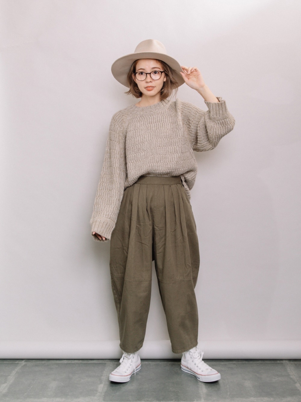 ベージュ系のニット/セーター、グリーン系のその他パンツ、ホワイト系のスニーカーを着用したレディースの秋コーディネートの1枚目の写真