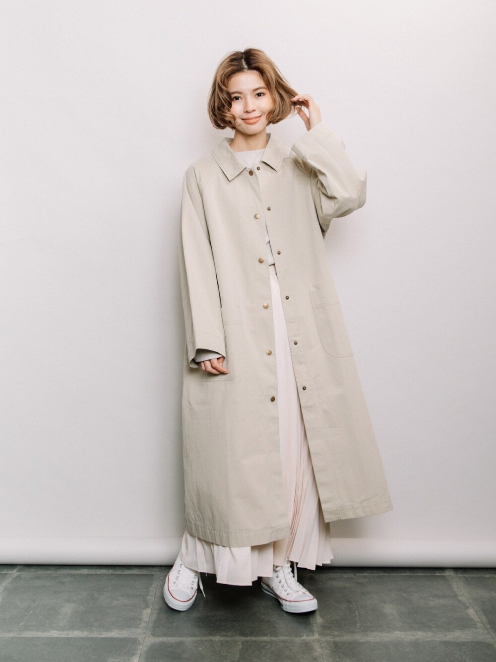 ベージュ系のステンカラーコート、ベージュ系のニット/セーター、ベージュ系のスカートを着用したレディースの春コーディネートの1枚目の写真