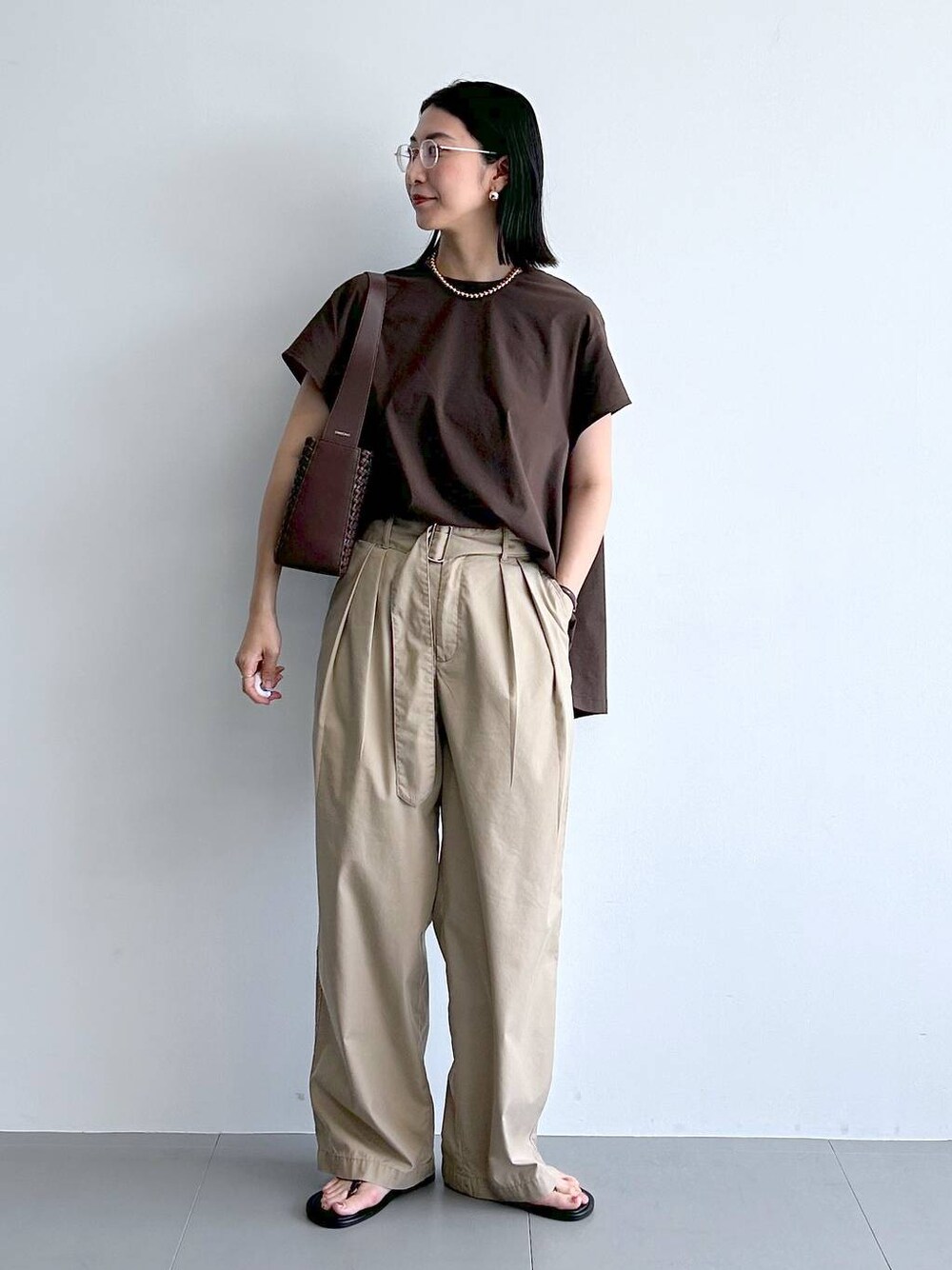 ベージュ系のチノパンツ、ブラウン系のサンダル、ブラウン系のハンドバッグを着用したレディースの夏コーディネートの1枚目の写真