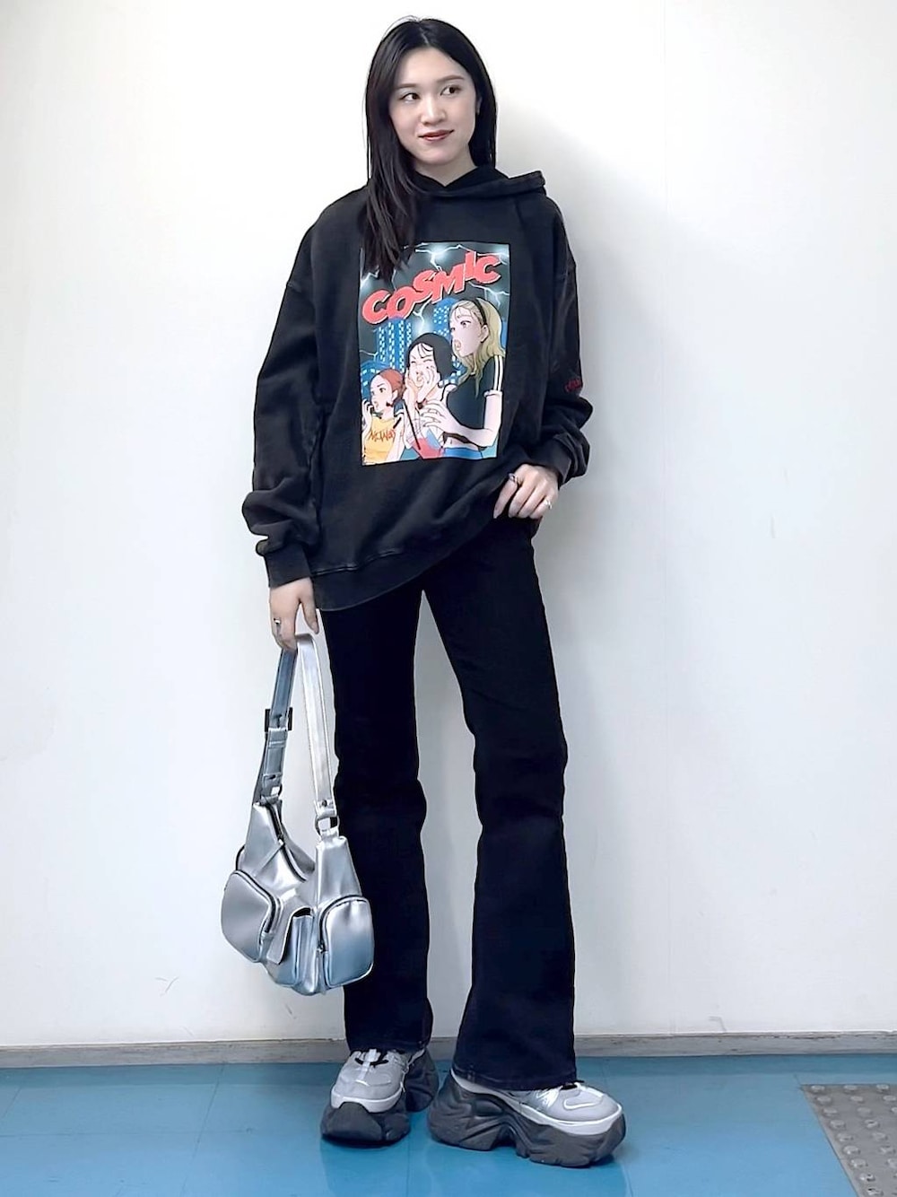 シルバー系のショルダーバッグ、ブラック系のデニムパンツ、ブラック系のパーカーを着用したレディースの冬コーディネートの1枚目の写真