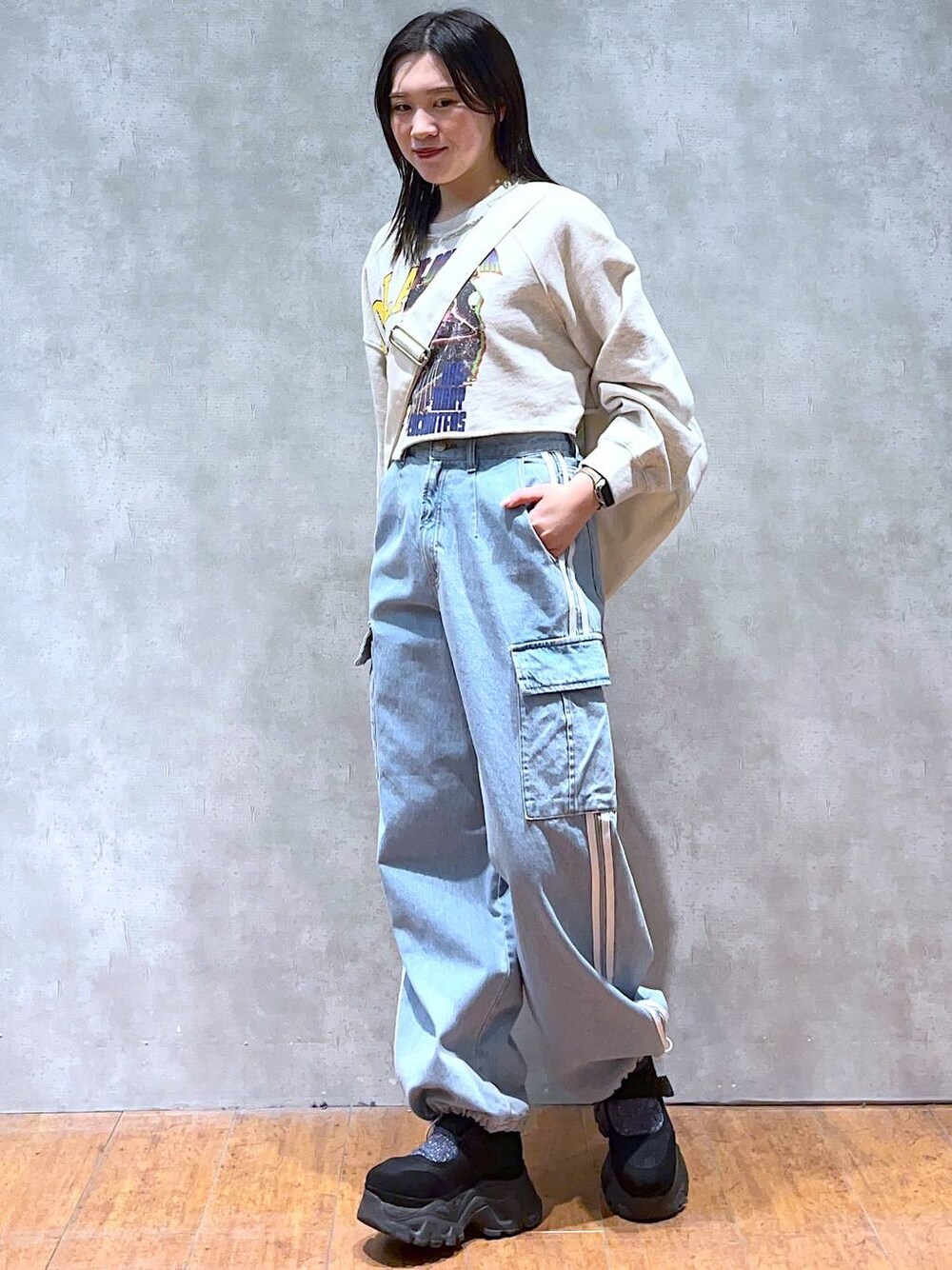 ベージュ系のスウェット、ホワイト系のショルダーバッグ、ブラック系のスニーカーを着用したレディースの春コーディネートの1枚目の写真