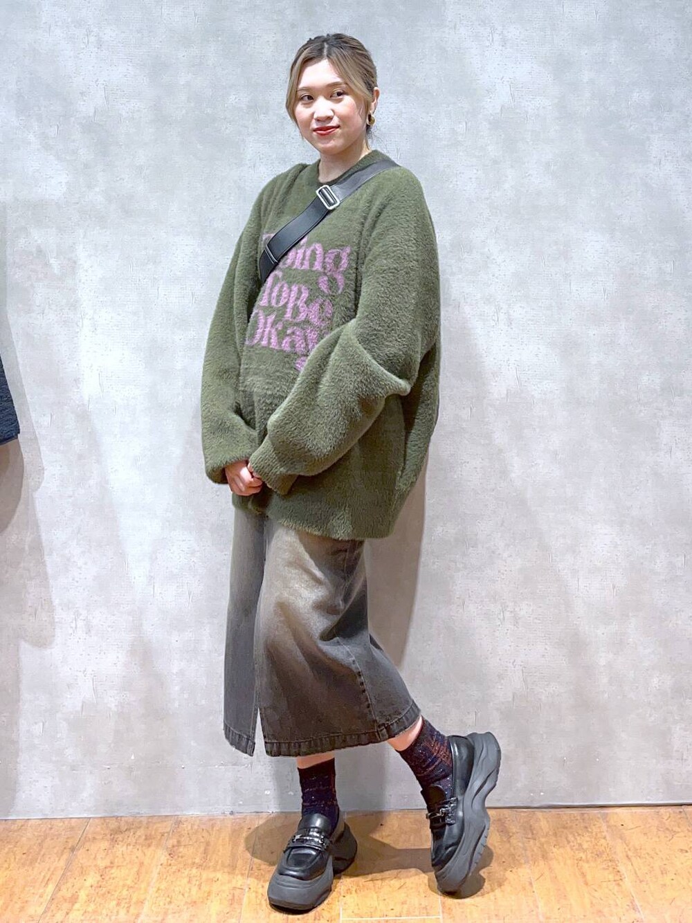 グリーン系のニット/セーター、ブラック系のショルダーバッグ、ブラック系のスカートを着用したレディースの秋コーディネートの1枚目の写真