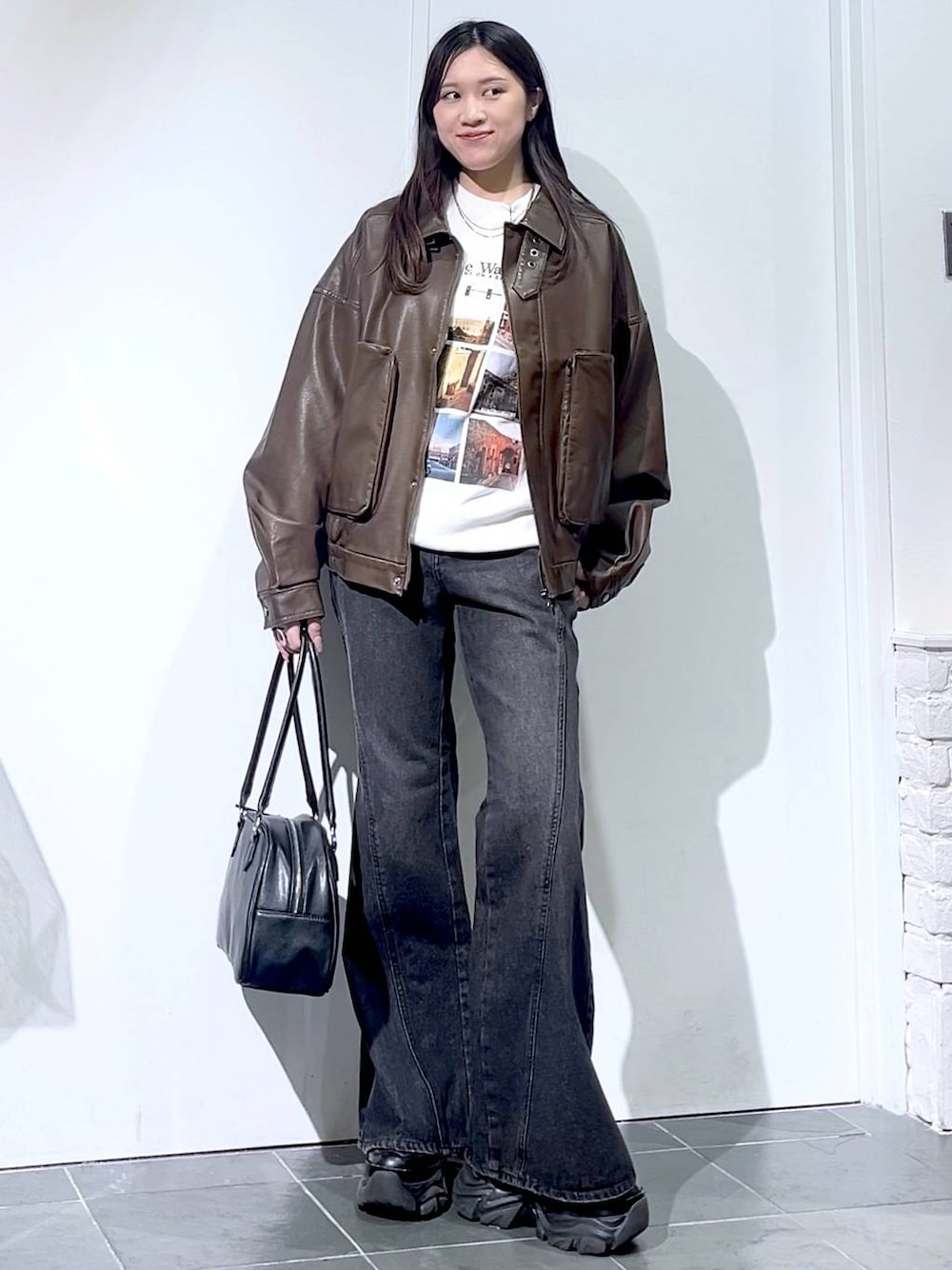 ブラック系のスニーカー、ブラック系のデニムパンツ、ブラック系のボストンバッグを着用したレディースの秋コーディネートの1枚目の写真