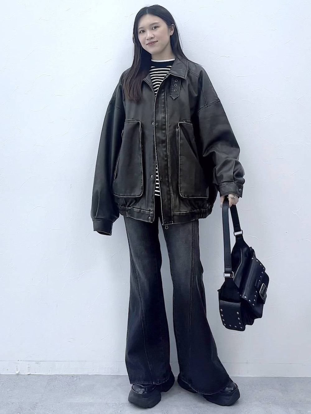 ブラック系のスニーカー、ブルー系のデニムパンツ、ブラック系のショルダーバッグを着用したレディースの秋コーディネートの1枚目の写真