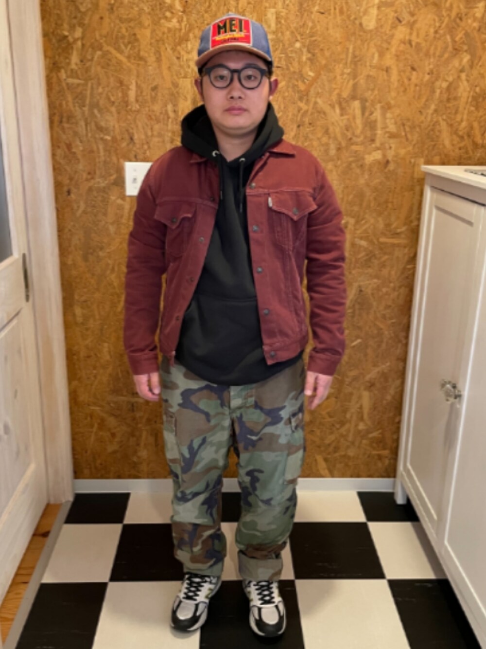 ブラック系のパーカー、レッド系のジャケット/アウター、グリーン系のカーゴパンツを着用したメンズの春コーディネートの1枚目の写真