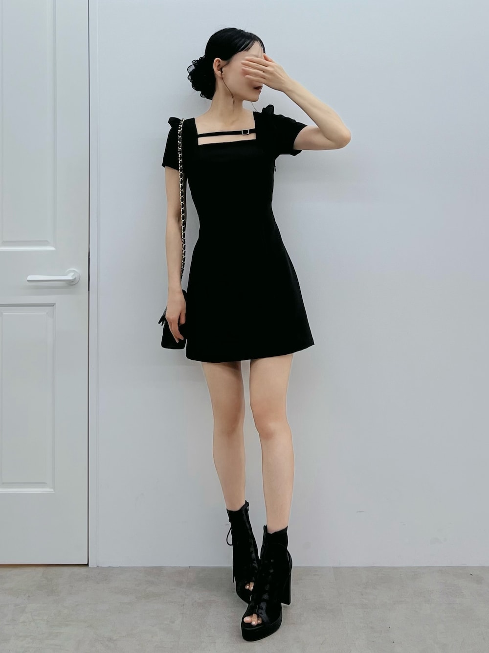 ブラック系のワンピース、ブラック系のブーツ、ブラック系のハンドバッグを着用したレディースの春コーディネートの1枚目の写真