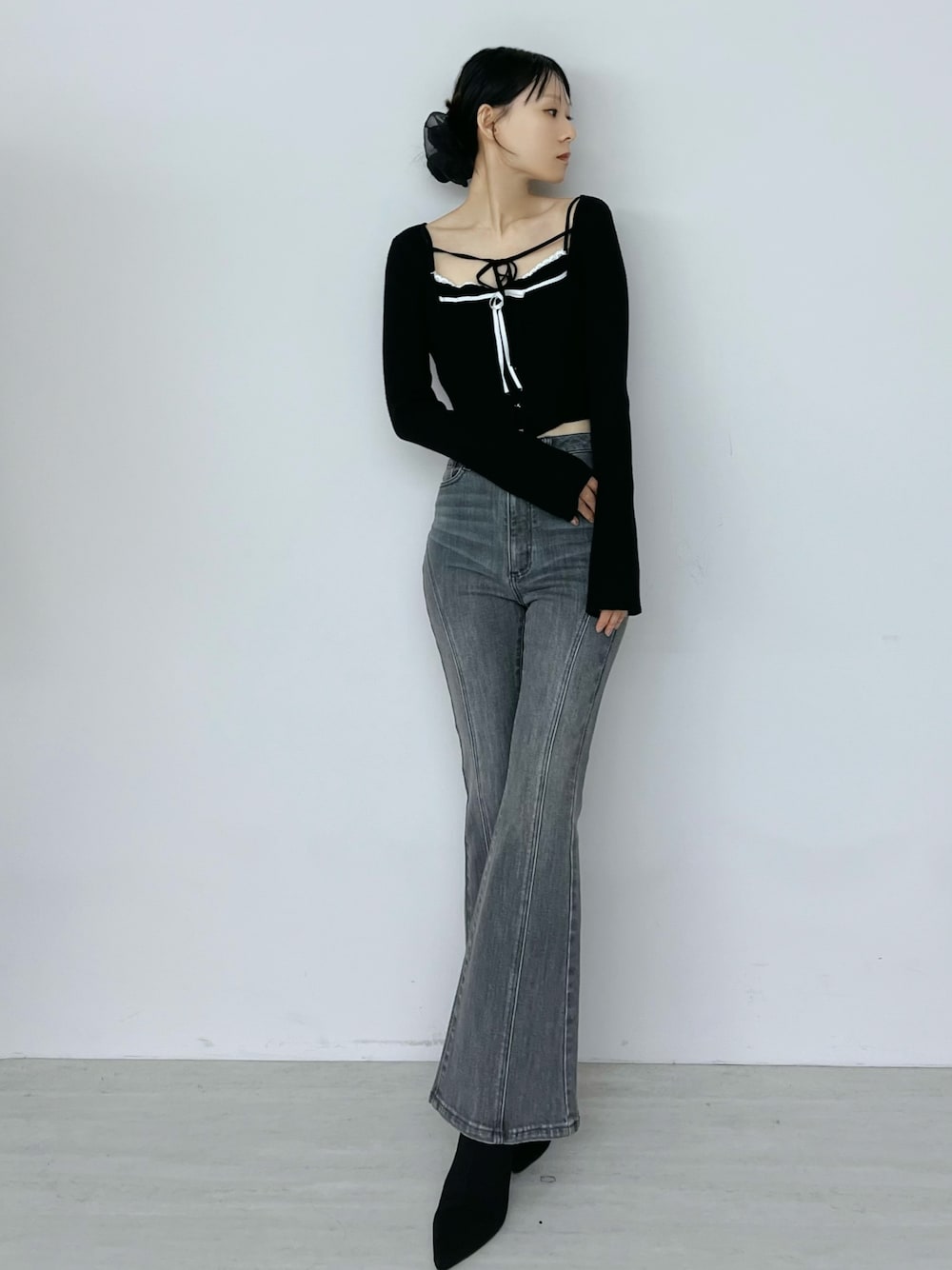 ブラック系のデニムパンツ、ブラック系のニット/セーター、ブラック系のブーツを着用したレディースの秋コーディネートの1枚目の写真