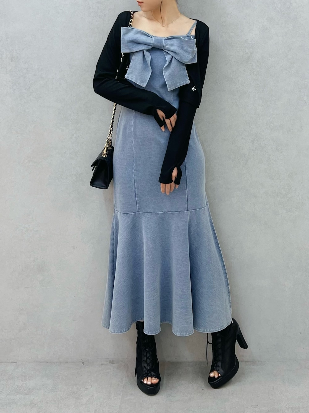 ブルー系のワンピース、ブラック系のTシャツ/カットソー、ブラック系のブーツを着用したレディースの春コーディネートの1枚目の写真