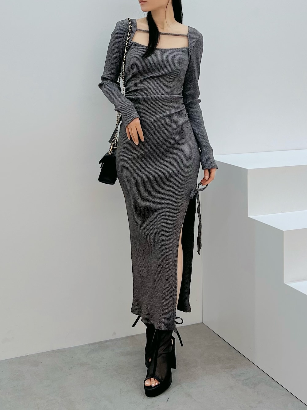 ブラック系のサンダル、グレー系のワンピース、ブラック系のハンドバッグを着用したレディースの春コーディネートの1枚目の写真