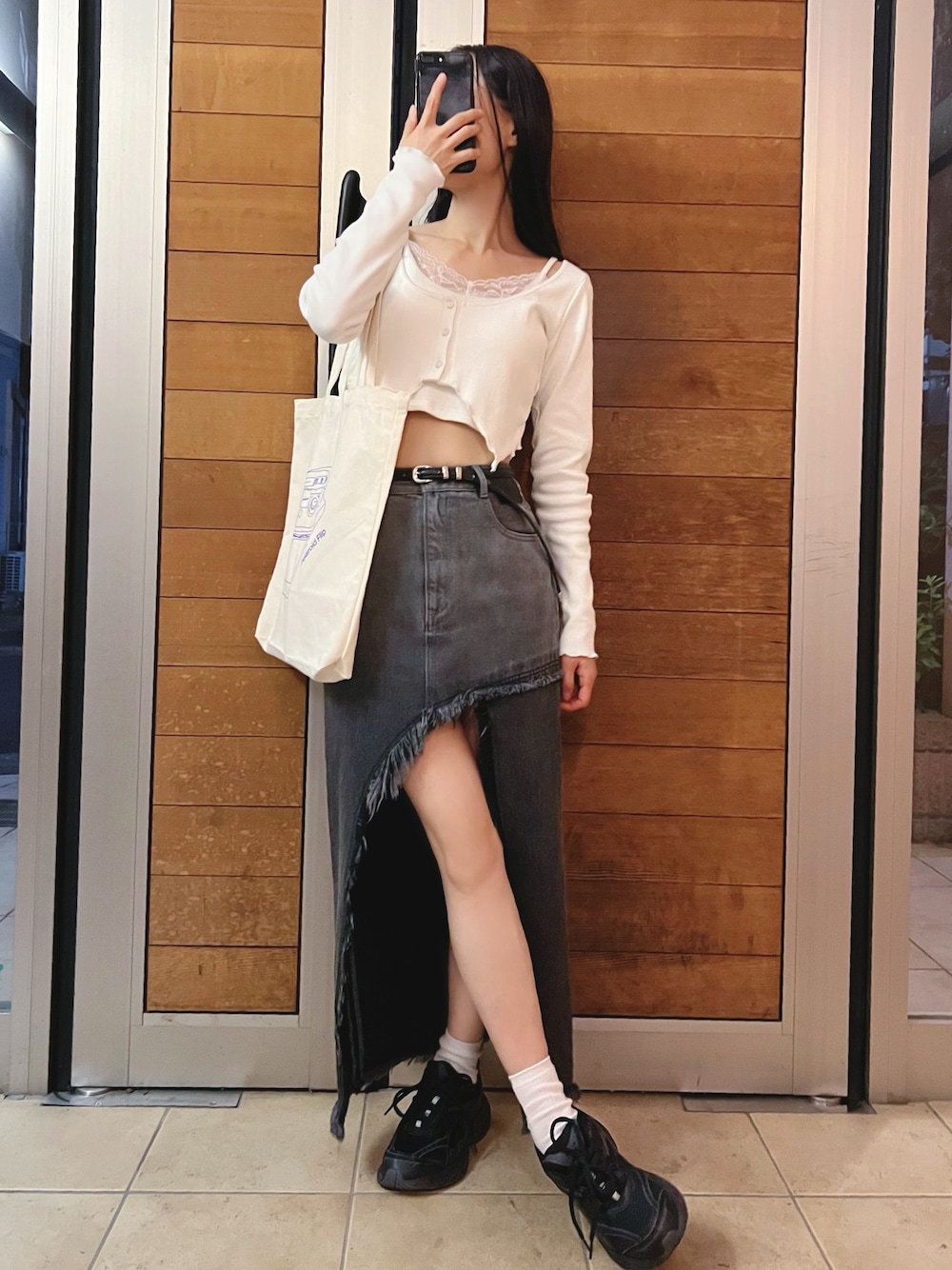 ブラック系のデニムスカート、ホワイト系のTシャツ/カットソーを着用したレディースの夏コーディネートの1枚目の写真