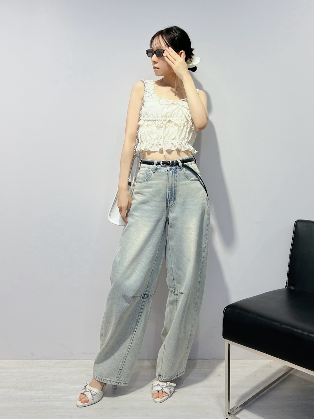 ブルー系のデニムパンツ、ホワイト系のサンダル、ホワイト系のキャミソールを着用したレディースの夏コーディネートの1枚目の写真
