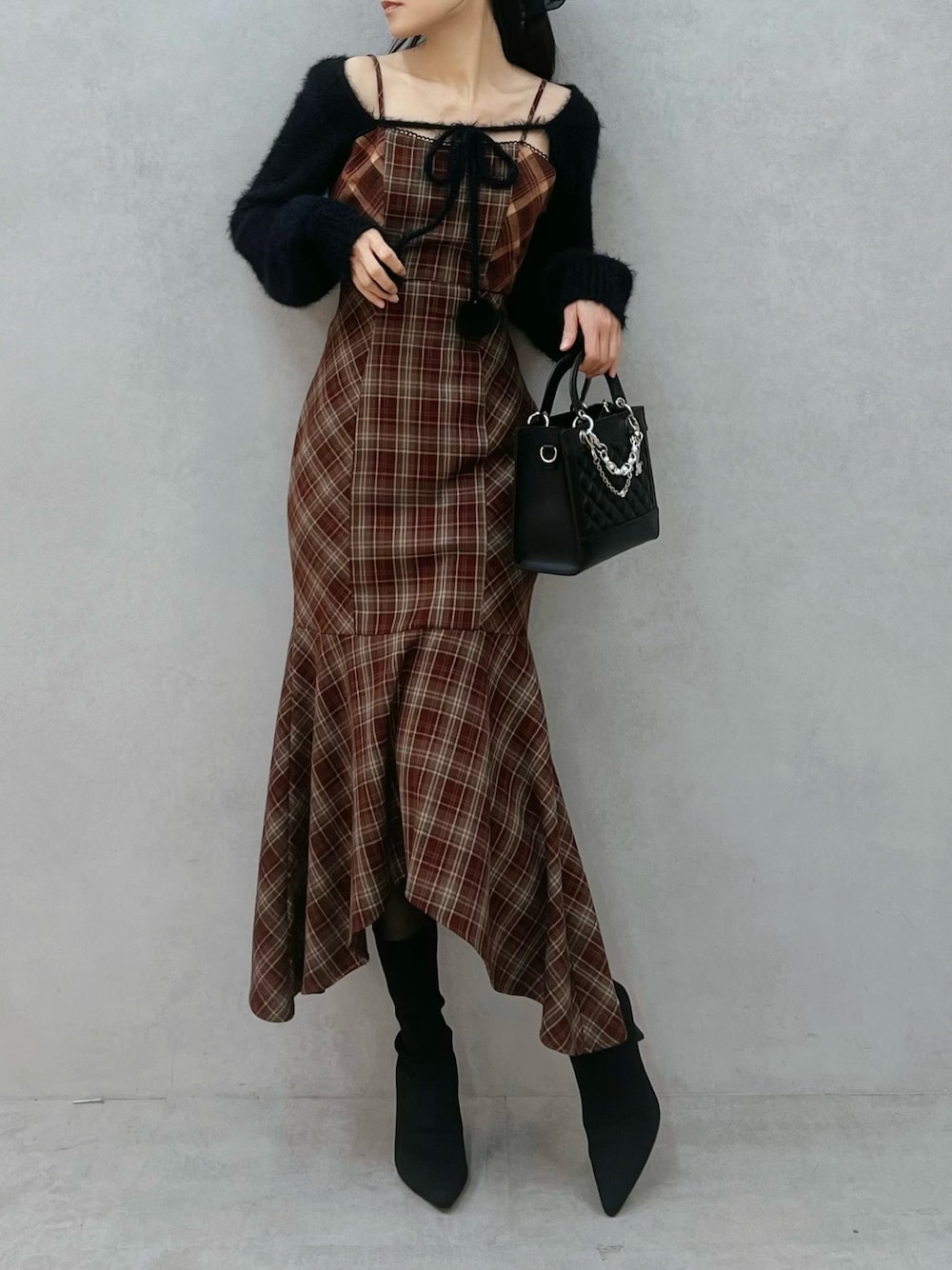 レッド系のワンピース、ブラック系のニット/セーター、ブラック系のブーツを着用したレディースの秋コーディネートの1枚目の写真