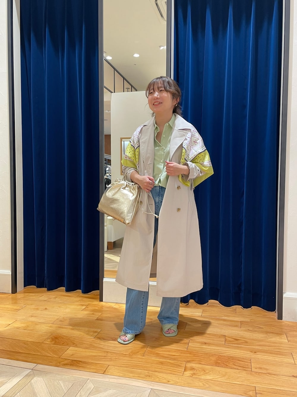 ベージュ系のトレンチコート、ブルー系のデニムパンツ、グリーン系のシャツ/ブラウスを着用したレディースの春コーディネートの1枚目の写真