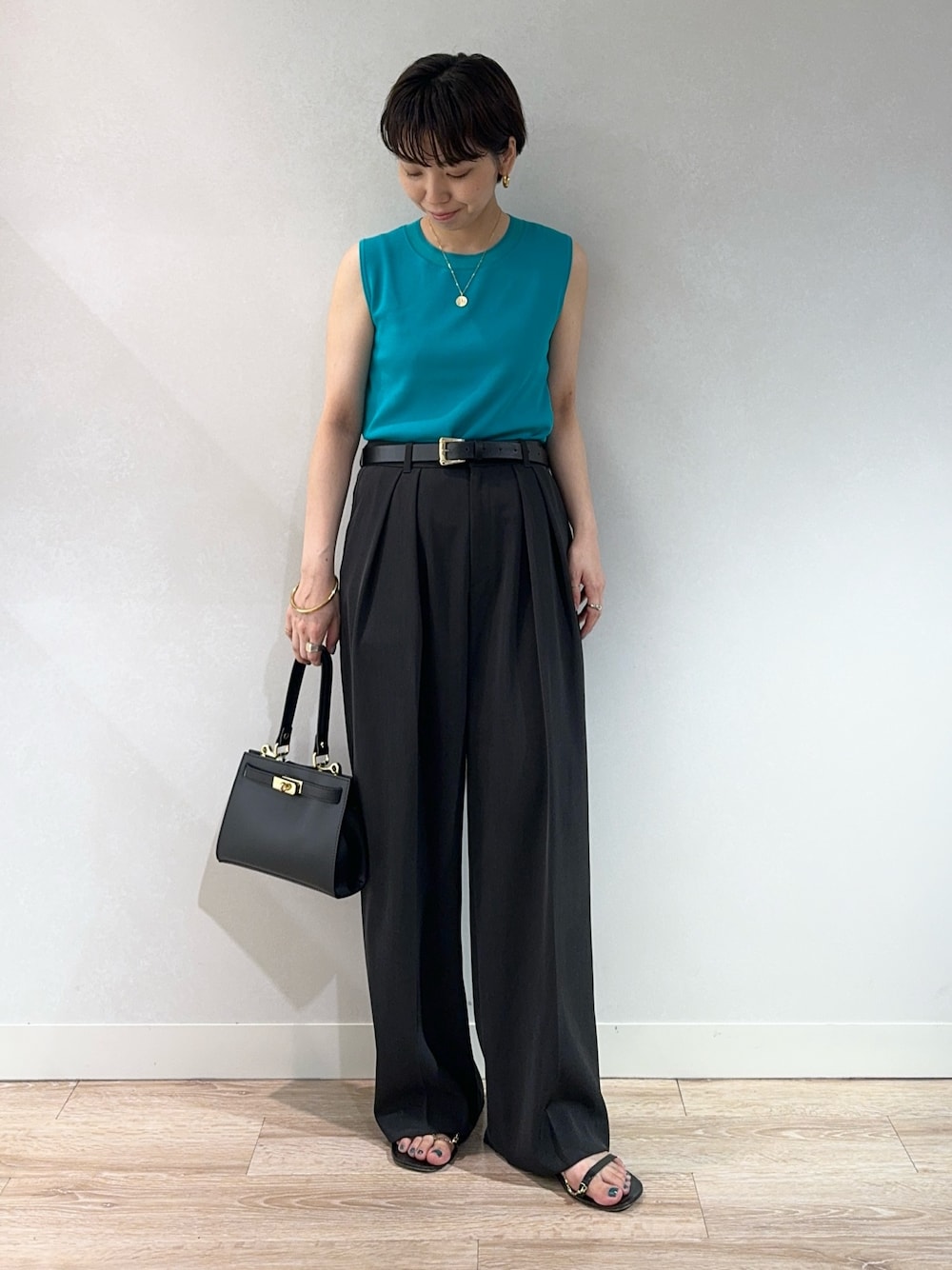 グリーン系のニット/セーター、グレー系のその他パンツ、ブラック系のベルトを着用したレディースの夏コーディネートの1枚目の写真
