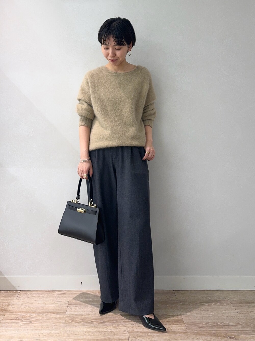 イエロー系のニット/セーター、グレー系のその他パンツ、ブラック系のショルダーバッグを着用したレディースの冬コーディネートの1枚目の写真